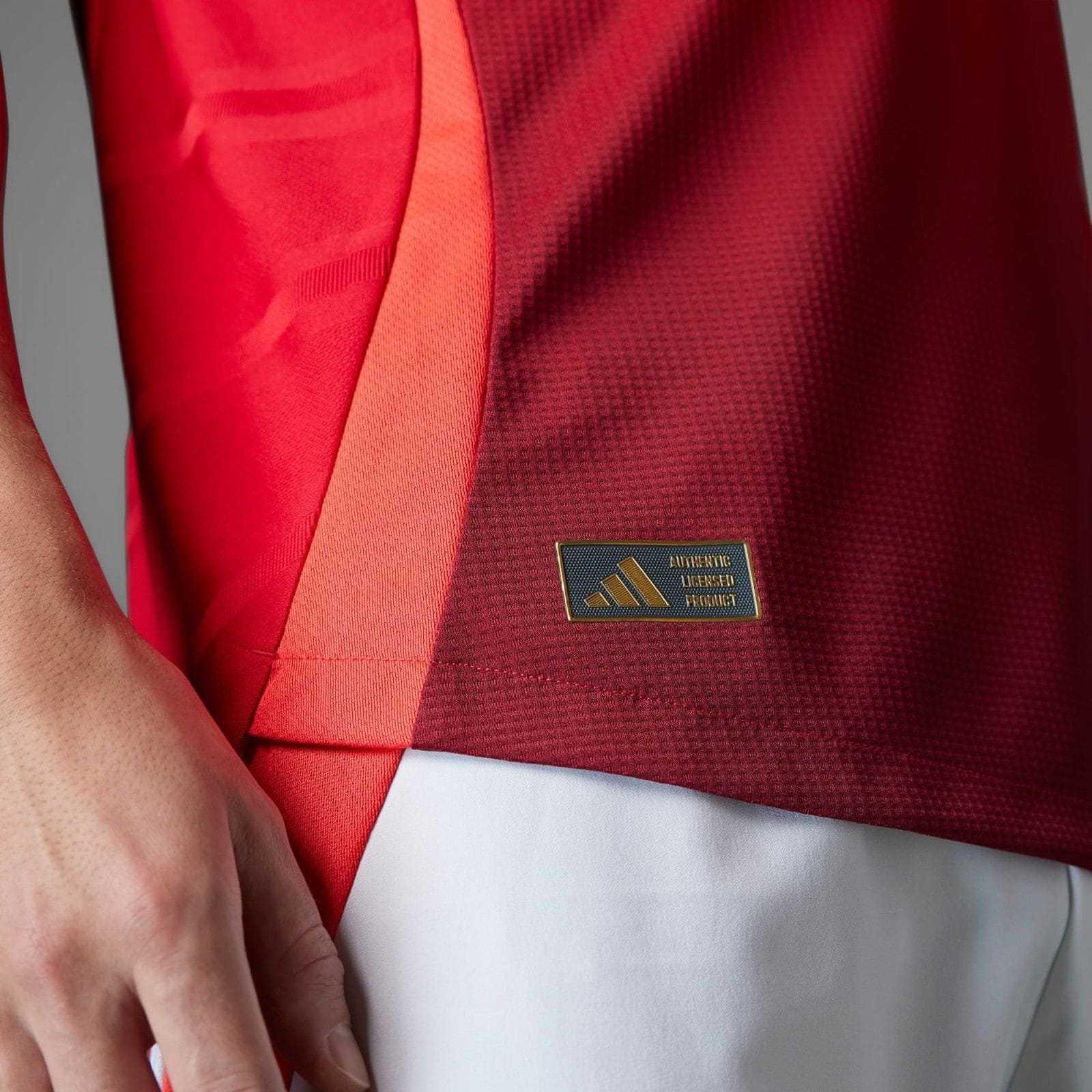 Zzx9vQ2gPlr3Iyi | UAE SPORT STORE Close-up of a red sports jersey featuring a small gold patch that reads 'Authentic Licensed Product'.