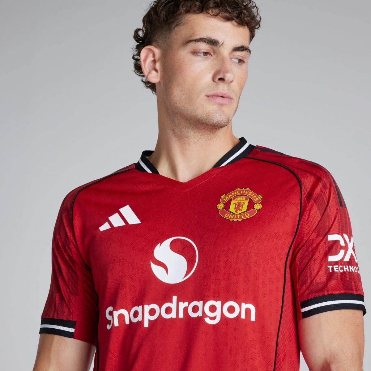 Man wearing a red Manchester United soccer jersey, facing slightly to the right, showing the team crest and Snapdragon sponsor text on the chest.
