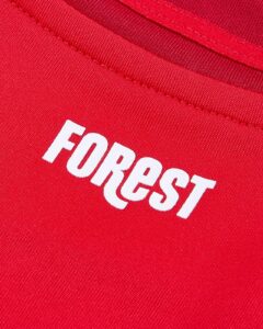 Close-up of red fabric with white bold uppercase text partially visible, near a seam.