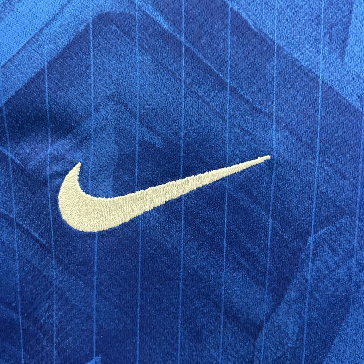 Close-up of a white Nike swoosh logo on blue denim fabric.