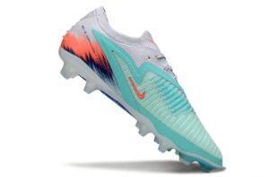 Mint green and turquoise soccer cleat with orange logo, angled on a white background, showcasing design and studded sole.