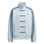Light blue Adidas track jacket with dark blue piping, stand collar, and Chinese-style knot toggles along the front zipper, logo on left chest.