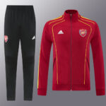 Arsenal red training jacket with yellow piping and crest, paired with black track pants featuring Adidas logo.