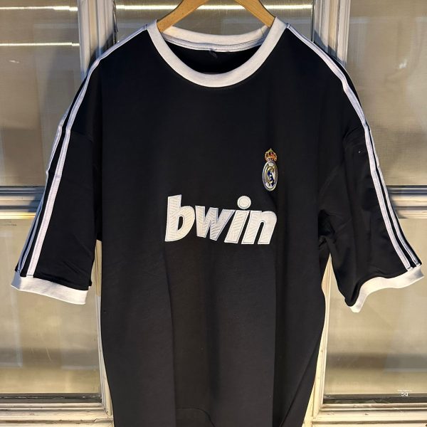 Black Real Madrid soccer jersey on a hanger, featuring white trim and the bwin logo on the front with the club crest on the chest.
