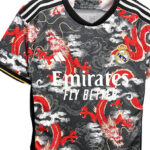 a2a08c6c-9842-4dee-946d-f069729316a0 | UAE SPORT STORE Real Madrid football jersey with a dragon pattern, sponsor text 'Emirates Fly Better,' crest on the chest, and black-and-white striped shoulders.