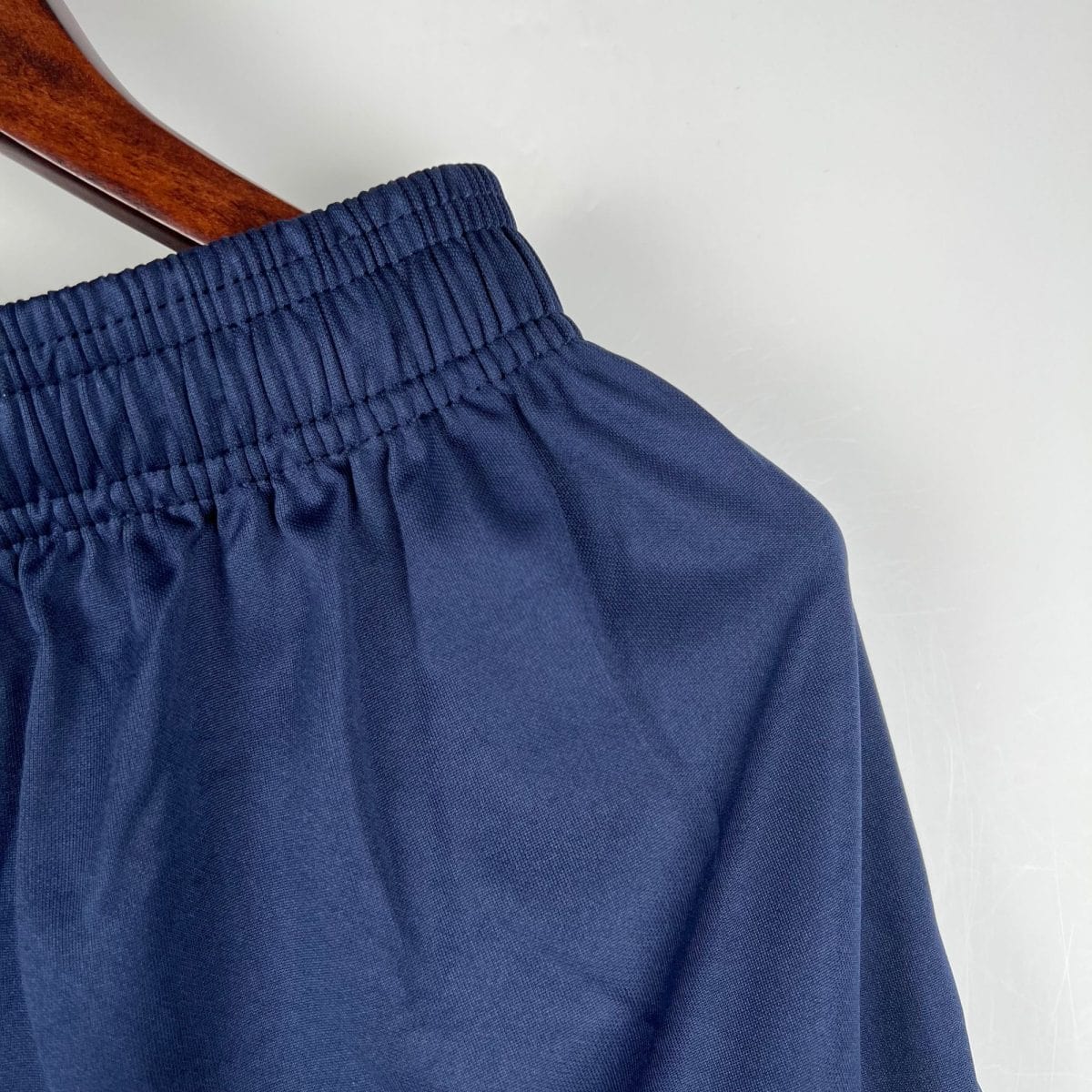 Close-up of navy blue fabric with an elastic smocked edge on a wooden hanger
