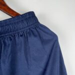 a3a69953_39c10265-2740-4804-91c1-fed0e0b076df | UAE SPORT STORE Close-up of navy blue fabric with an elastic smocked edge on a wooden hanger