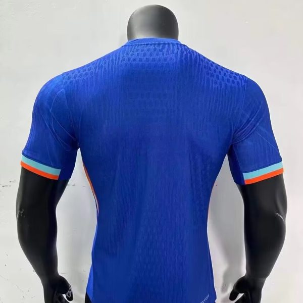 Back view of a cobalt blue athletic jersey on a mannequin, featuring a subtle upper-back pattern and orange-and-light-blue striped sleeve cuffs.