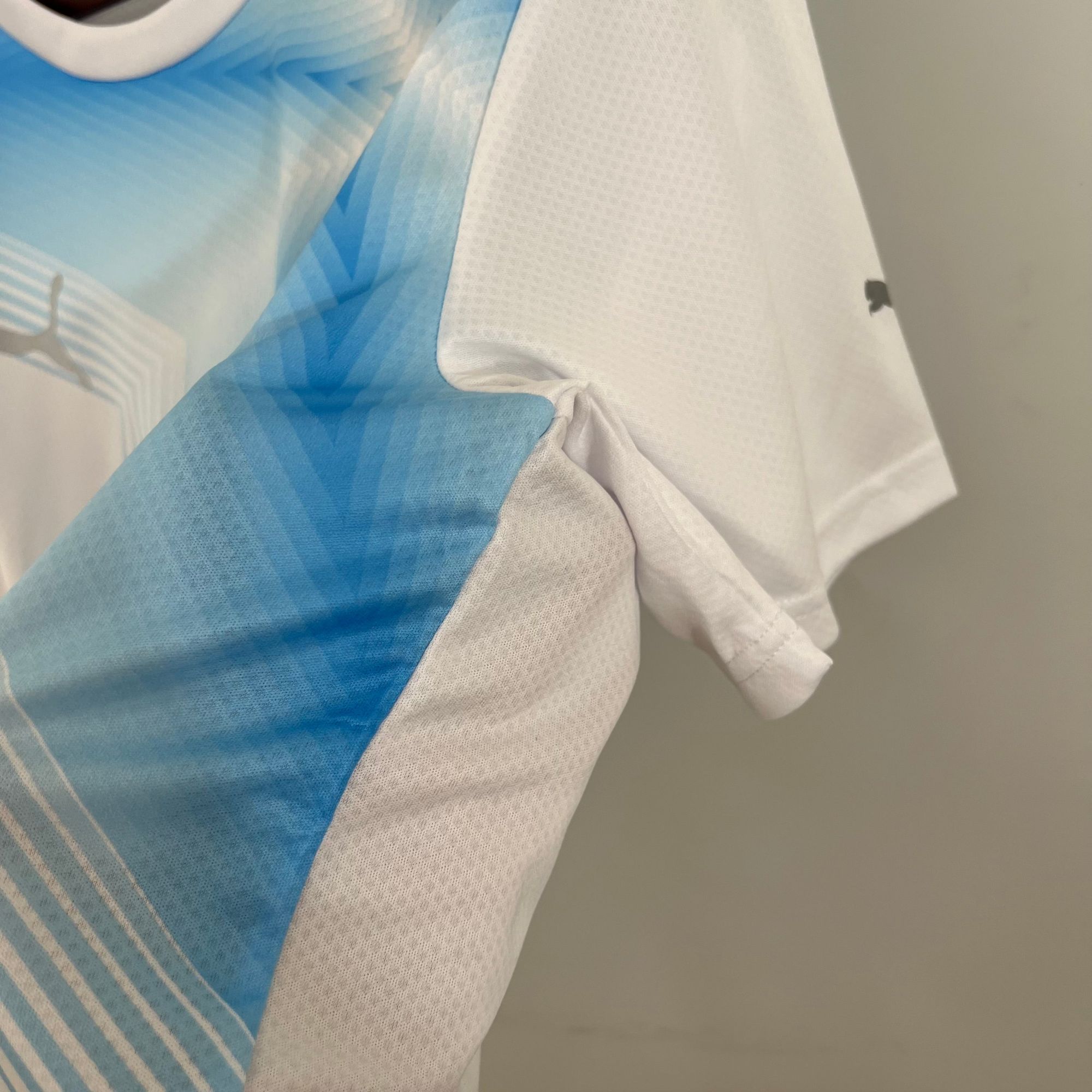 a3f44936_2fd2e2fa-38e6-4f04-aed2-5c1137f08c27 | UAE SPORT STORE Close-up of blue striped fabric laid over a light gray surface and a white textured cloth nearby.