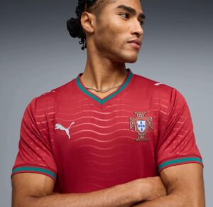 a4030753-7bb7-4a1c-9d5a-1a4e662b16a1 | UAE SPORT STORE Young man wearing a red Portugal national team jersey with a Puma logo, looking to the right, arms crossed.