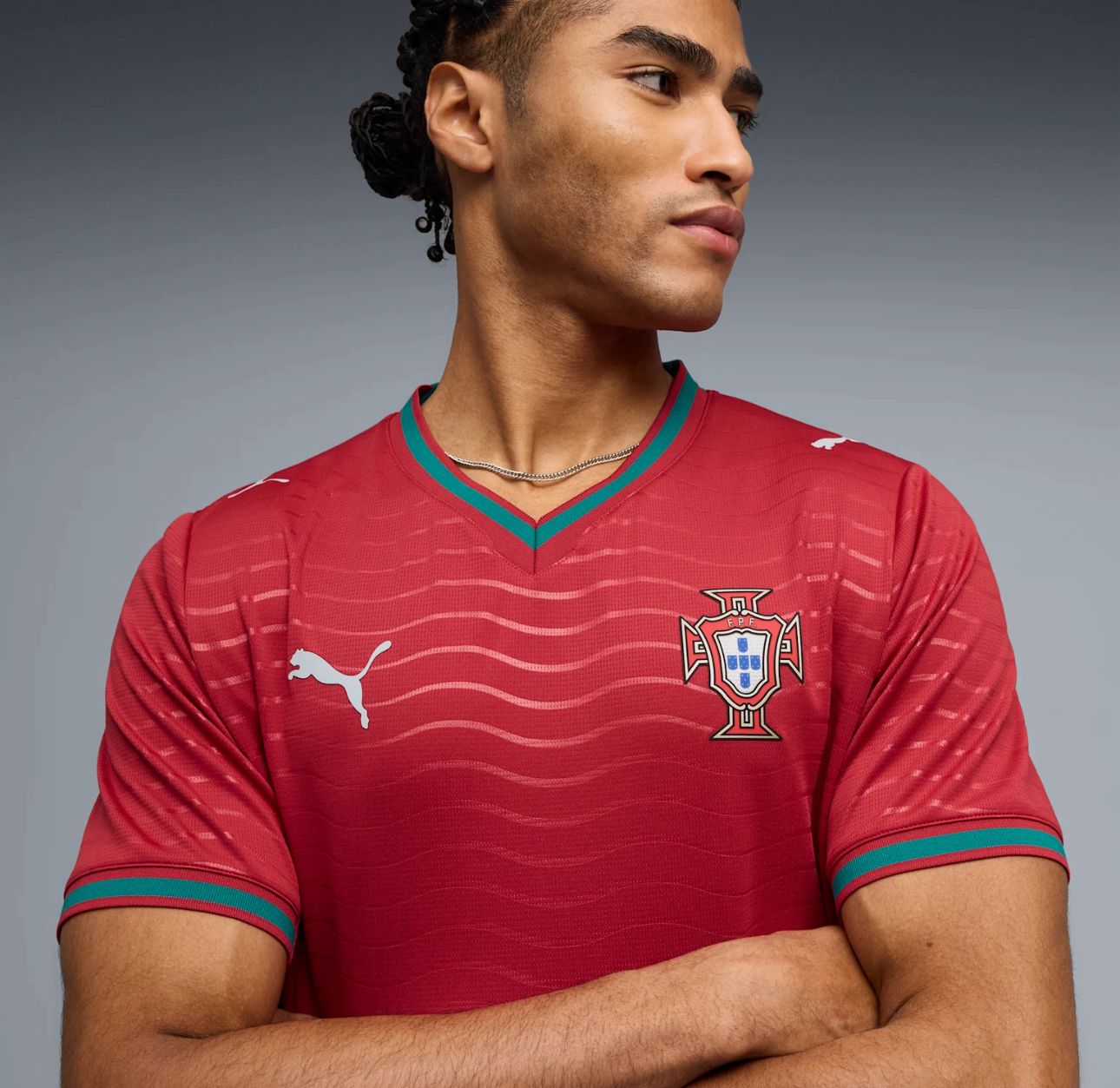 a4030753-7bb7-4a1c-9d5a-1a4e662b16a1 | UAE SPORT STORE Young man wearing a red Portugal national team jersey with a Puma logo, looking to the right, arms crossed.