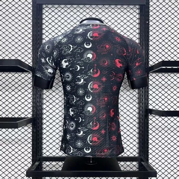 Black short-sleeve shirt with white and red sun, moon, and star patterns on a mannequin in a metal grid display.