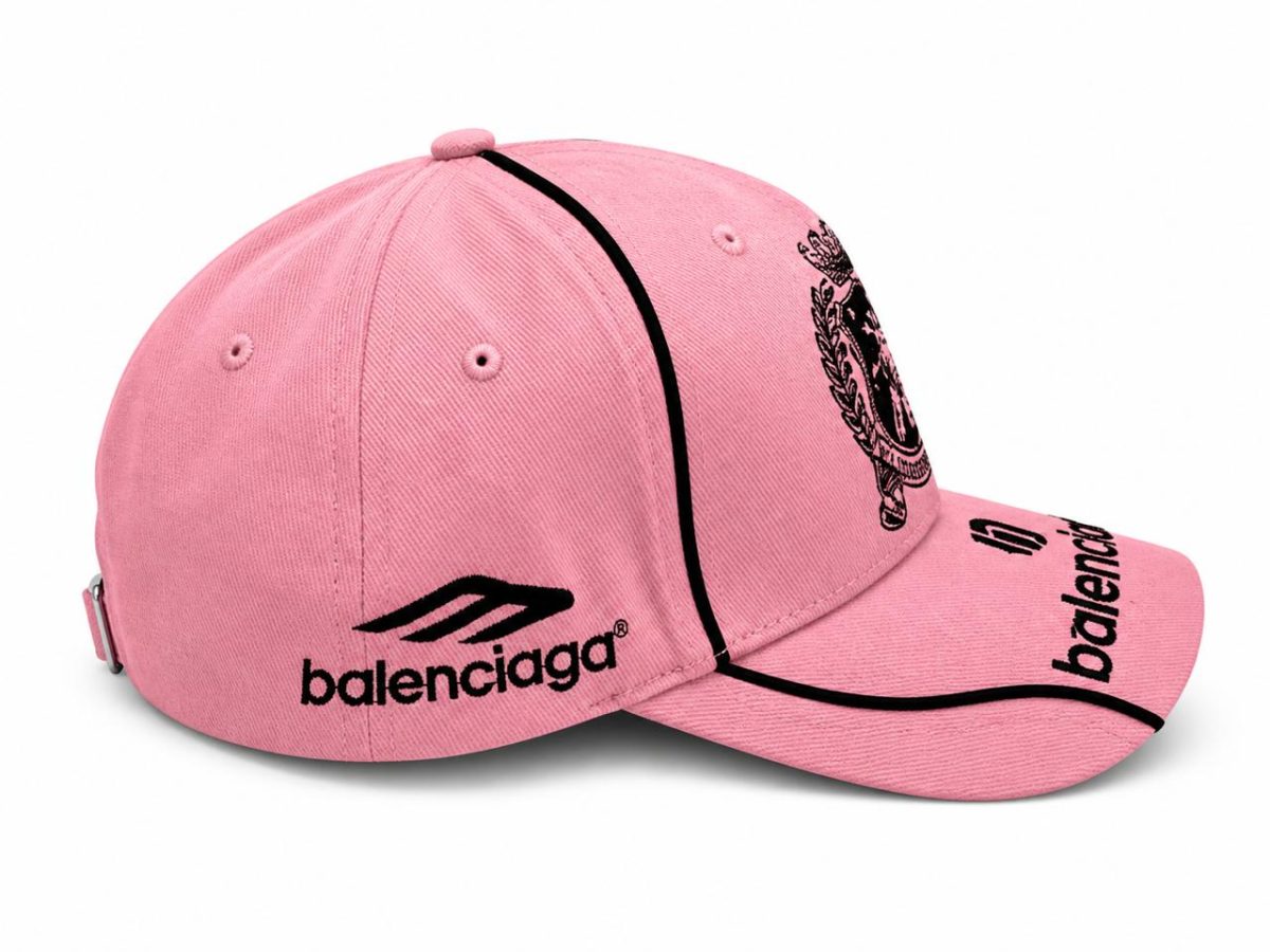 Pink baseball cap with Balenciaga logo on the side and a black piping outline, adjustable back strap, pink fabric.