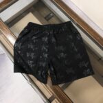 Black shorts with an elastic waistband featuring an all-over gray Dior Paris logo pattern.