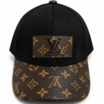 Black baseball cap with a brown LV monogram print on the curved brim and a leather LV patch on the front.