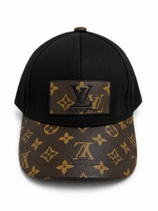 Black baseball cap with a brown LV monogram print on the curved brim and a leather LV patch on the front.