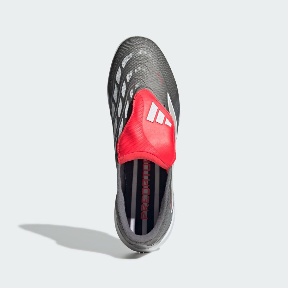 Top-down view of a gray Adidas athletic shoe with a red tongue and white stripes, showing a textured mesh upper.