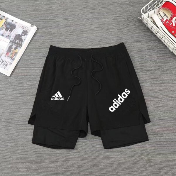Black Adidas athletic shorts with a drawstring, featuring large white Adidas logo on the right leg and a smaller logo on the left thigh.