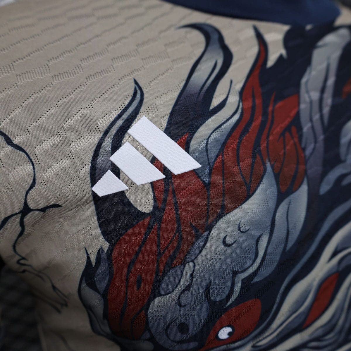 Close-up of patterned fabric with red and dark blue abstract shapes on a gray background, with white ribbon-like pieces laid on top.