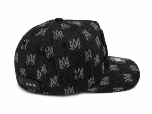 a6714065-e29f-4c89-9879-ecd6889720af | UAE SPORT STORE Black denim cap with a repeating white logo pattern and an Amiri label on the back, curved brim with a circular patch on the top.