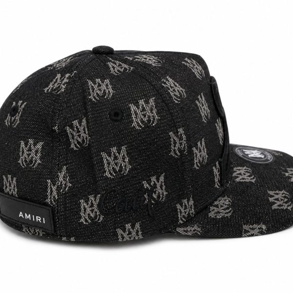 Black denim cap with a repeating white logo pattern and an Amiri label on the back, curved brim with a circular patch on the top.