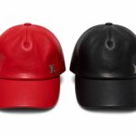 Two leather baseball caps, one red and one black, with silver LV logos on the front panels.