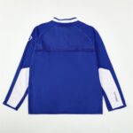 Back view of a blue athletic jacket with white sleeve panels and a white collar trim.