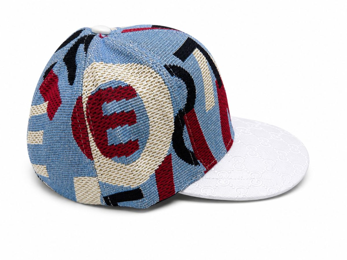 Colorful baseball cap with a blue, red, and beige embroidered pattern and a white textured brim, shown from a side angle.