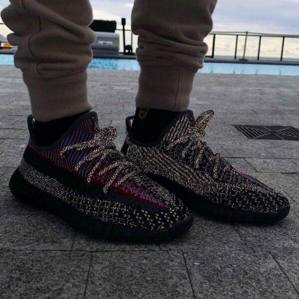 Person wearing patterned running shoes standing on a gray tiled surface near a pool.