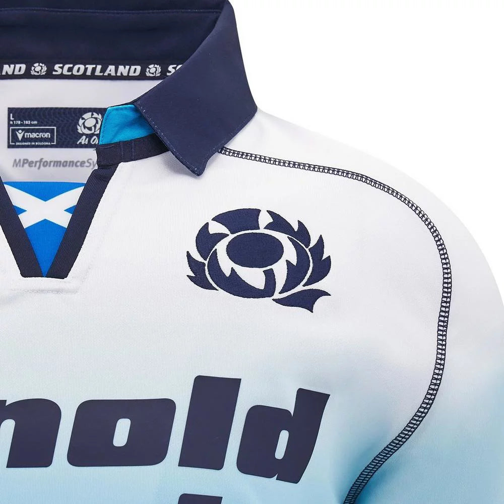 a7ed71f94cb8cdeec26bc484846fa6e5 | UAE SPORT STORE Close-up of a white-to-light-blue rugby jersey with a dark blue collar, a circular Scottish thistle crest on the chest, and bold navy lettering across the front.