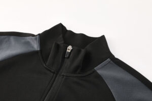 Close-up of a black jacket collar with a silver zipper and gray shoulder panels.