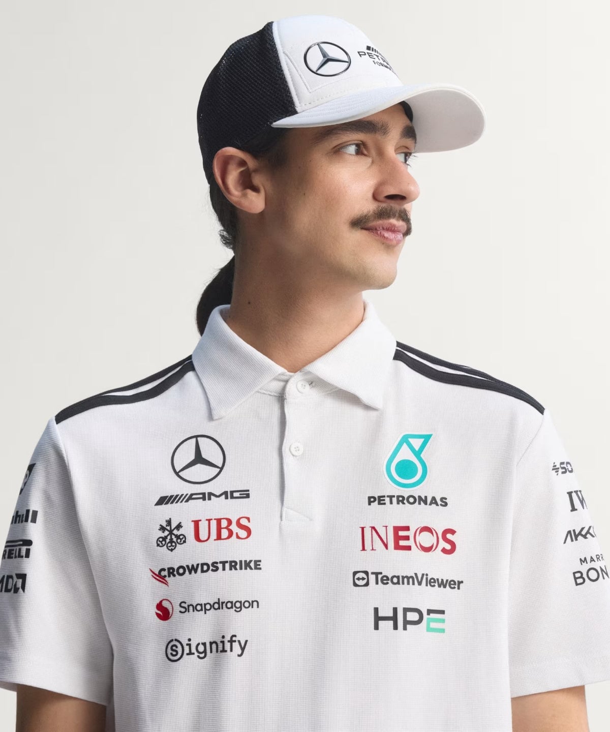 a890494fb22457477240f6365dbe5d5c-1200x1440-1 | UAE SPORT STORE Portrait of a man in a white polo shirt with sponsor logos, wearing a white cap, looking to the right.