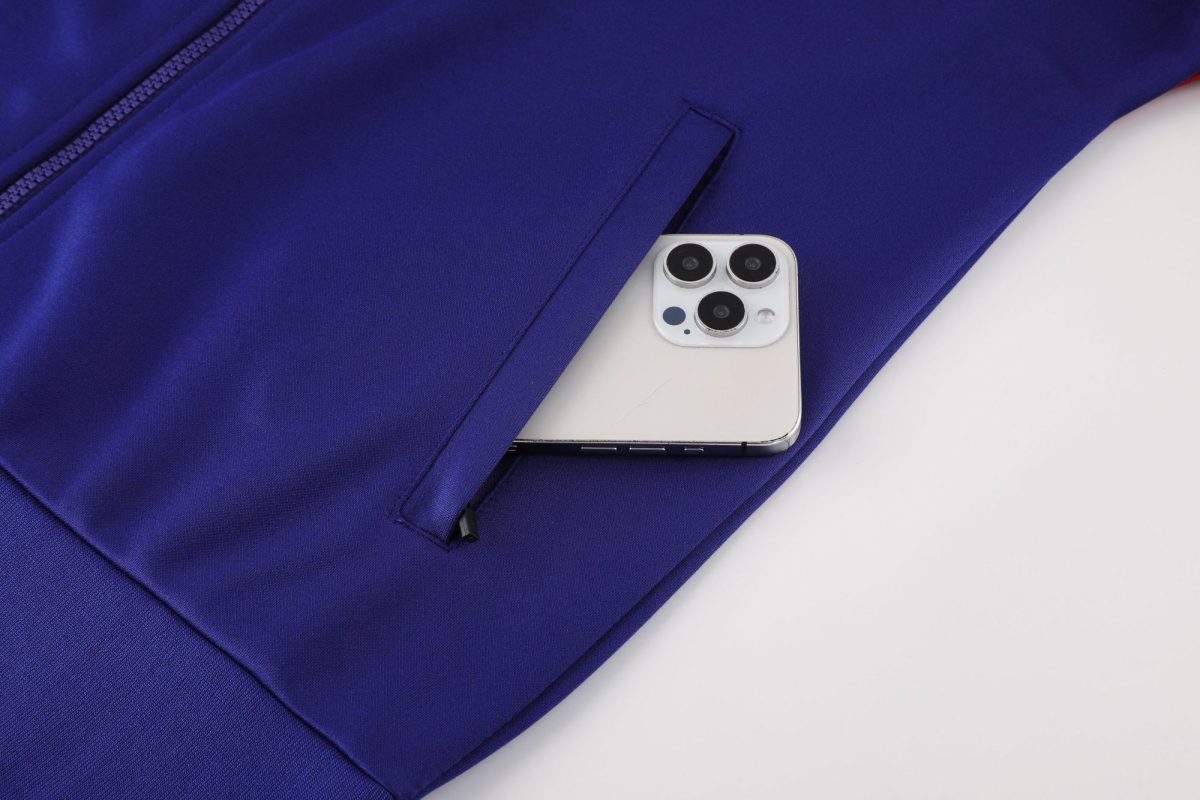 Purple fabric bag with a zipper pocket, a white iPhone partially visible inside the pocket.