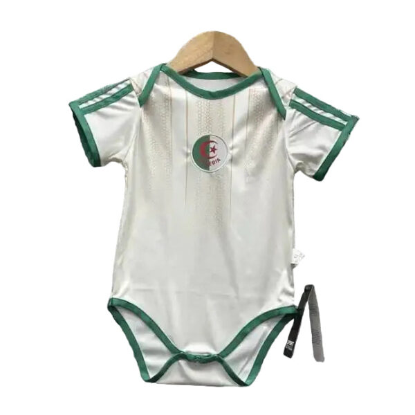 White baby onesie with green trim on sleeves and leg openings, hanging on a wooden hanger; circular patch with crescent and star on chest