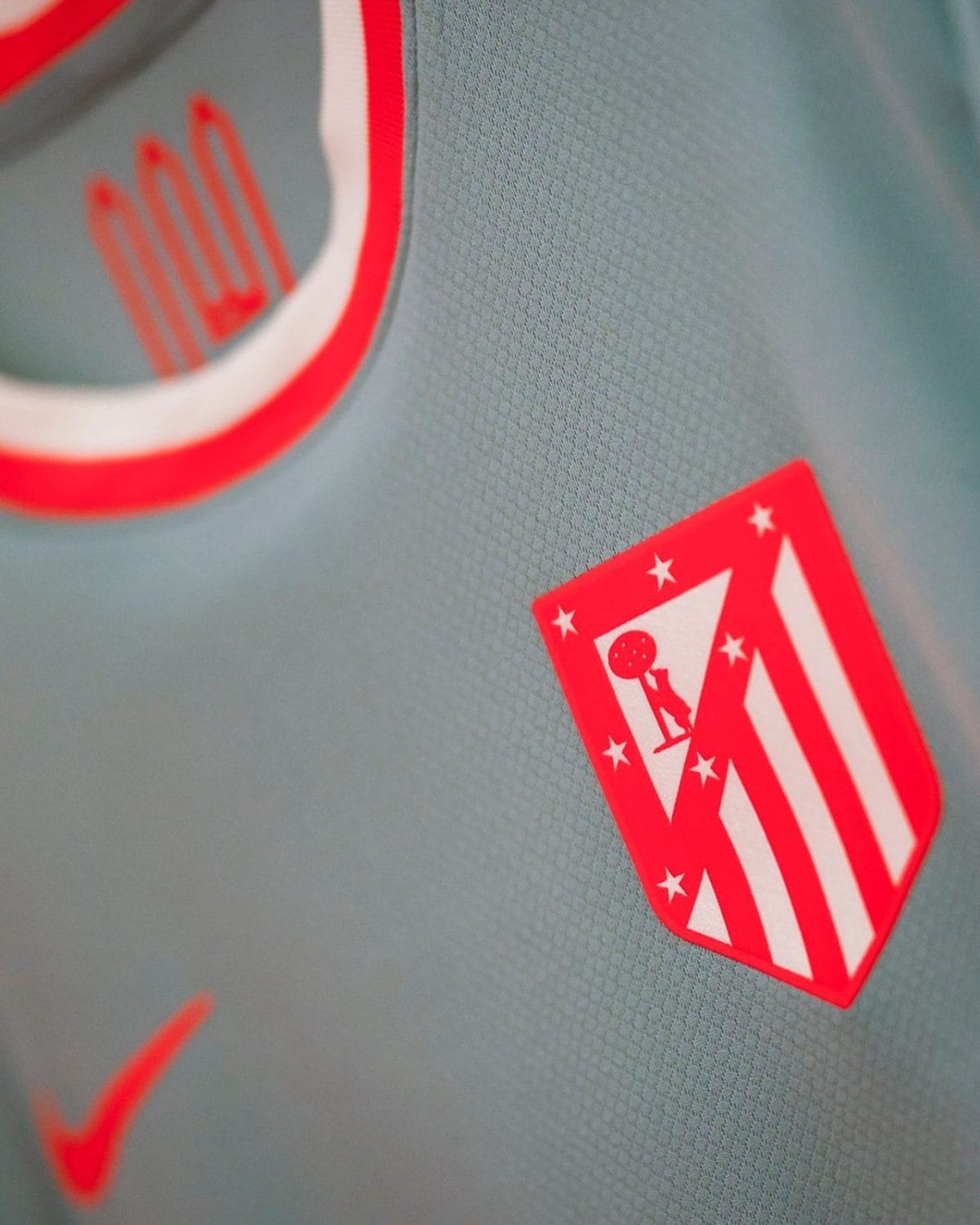 Close-up of an Atlético Madrid crest on a light blue sports jersey.