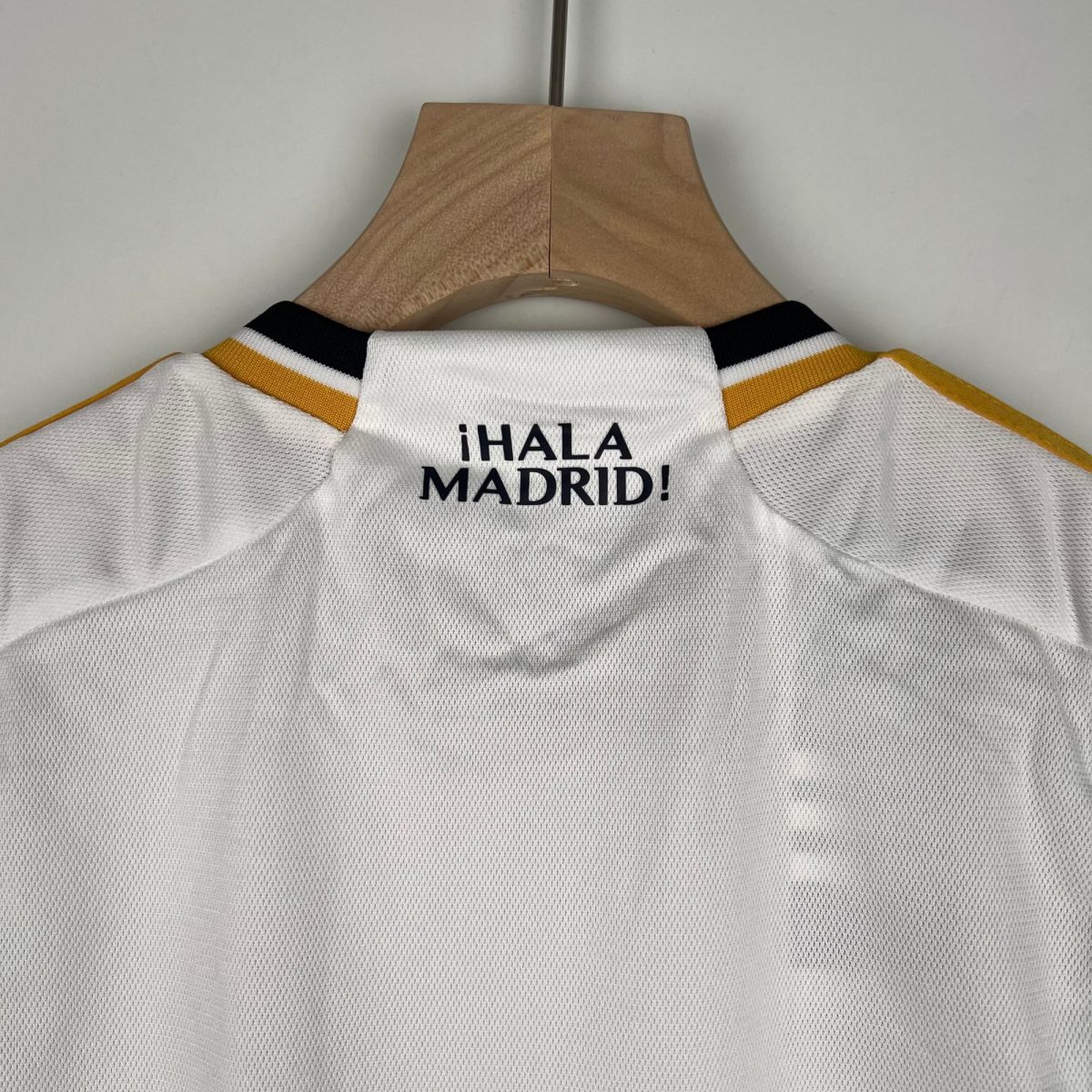 White sports jersey on a wooden hanger, with the bold text '¡HALA MADRID!' visible on the chest area.