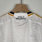 White sports jersey on a wooden hanger, with the bold text '¡HALA MADRID!' visible on the chest area.