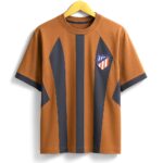 Brown T-shirt with bold dark blue vertical stripes and a small shield emblem on the chest, on a wooden hanger