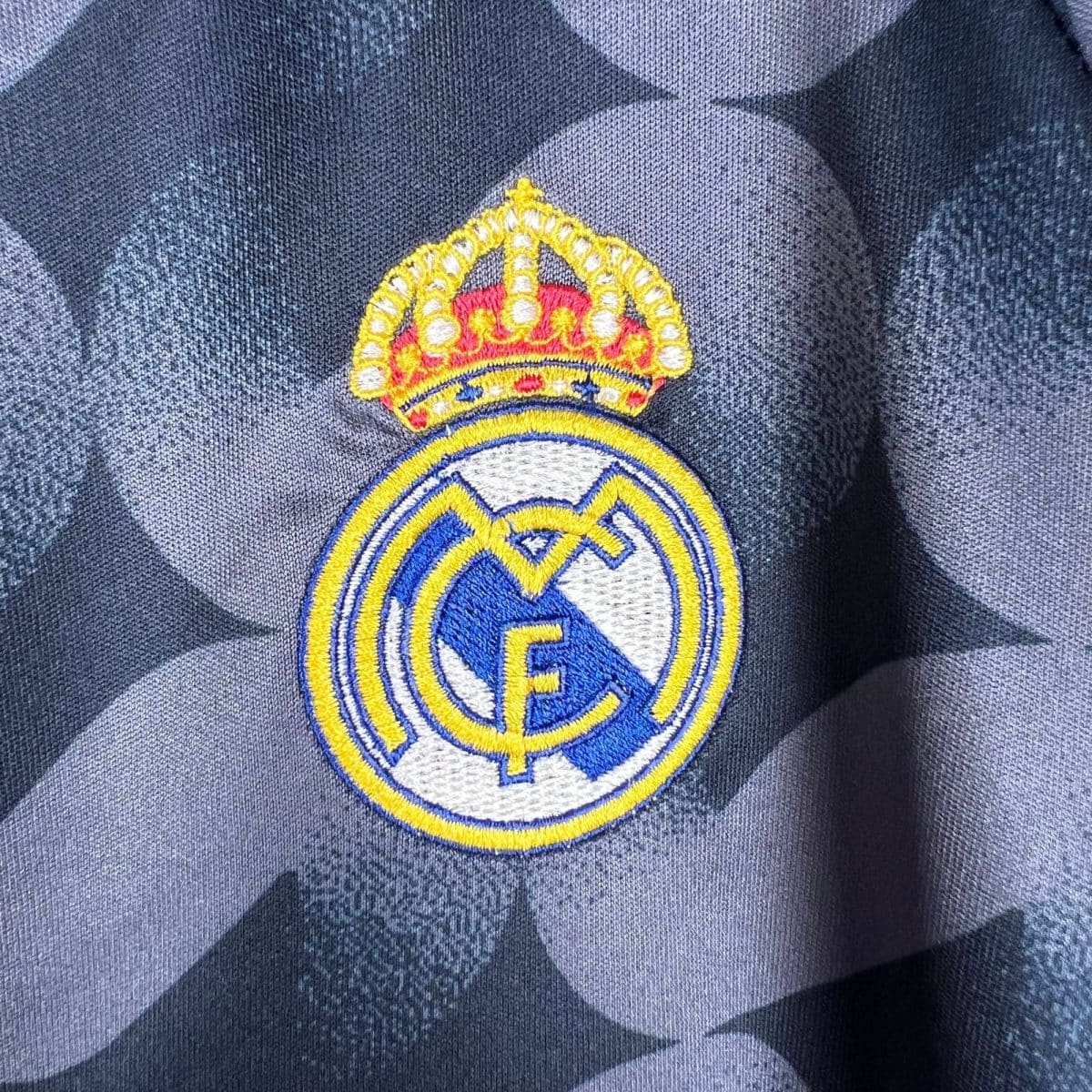 Close-up of an embroidered crown patch on dark blue denim fabric.