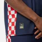 Close-up of a navy football jersey with a red-and-white checker stripe and a small patch reading AUTHENTIC LICENSED FOOTBALL with a Puma logo.