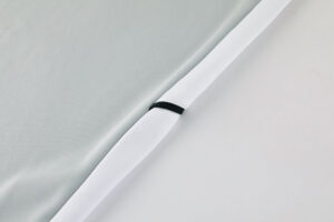 Close-up of a light gray bedding cover with a white zipper along the edge.