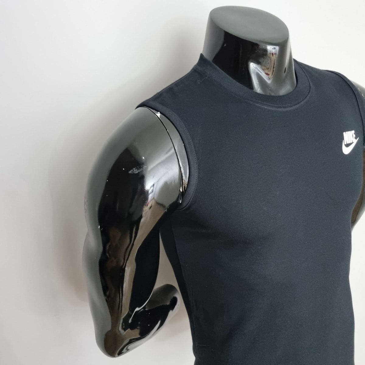 Black Nike sleeveless shirt on a glossy chrome mannequin torso; product display.