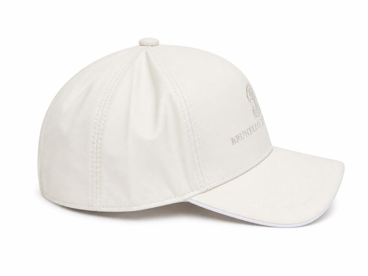 White baseball cap with a curved bill and small top button, featuring an embroidered emblem on the side.