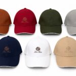 Seven baseball caps in orange, red, olive, gray, navy, white, and tan with an embroidered crest and 'Loro Piana' text visible on each cap.