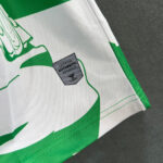 Close-up of white fabric with green graphic and a shield-shaped 'Certified Authentic' label.