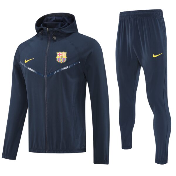 Navy blue FC Barcelona training jacket with crest and yellow Nike swoosh, alongside matching navy pants with a yellow Nike logo.