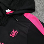Black hoodie with a pink lion crest patch on the chest and a bright pink diagonal strap across the shoulder area.