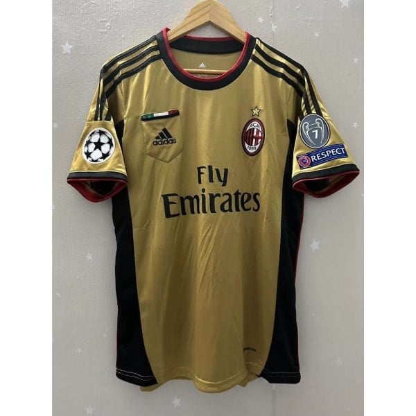 ac_milan_1314_season_retro_jer_1706023808_dabe789c_progressive - UAE SPORT STORE AC Milan gold goalkeeper jersey on a wooden hanger, with Fly Emirates sponsor and Champions League badge on the sleeve.