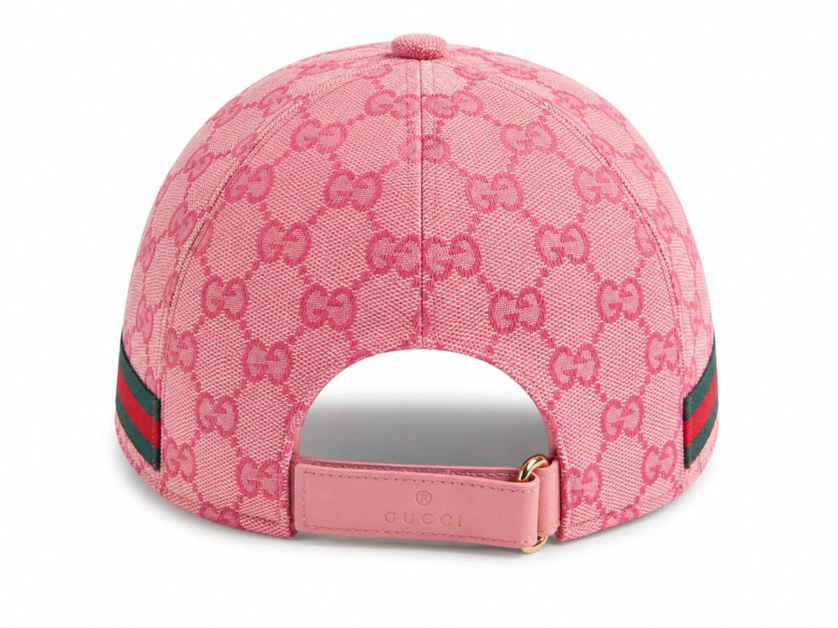 Pink Gucci baseball cap with allover GG monogram, back view showing the pink leather strap and gold buckle, with a green-red-green web stripe on the side.