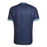 Back view of a navy polo shirt with small light-blue diamond patterns and mint trim on the collar and sleeves.”] ,